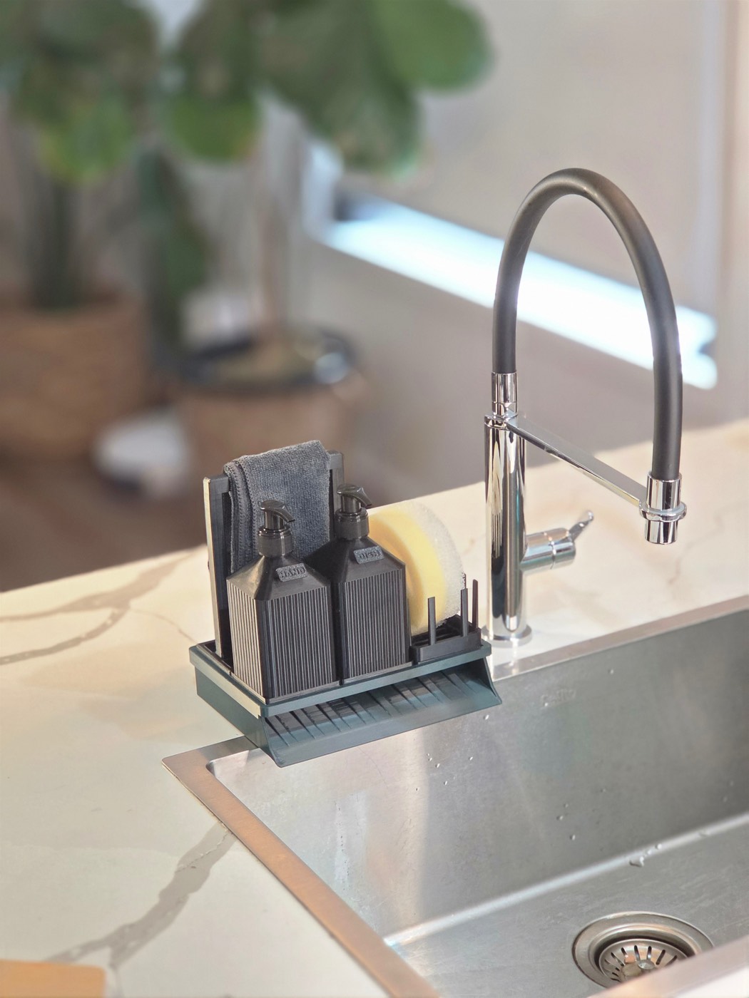 The Everything Station on a kitchen sink with two soap pumps, a cloth rail and the draining tray.